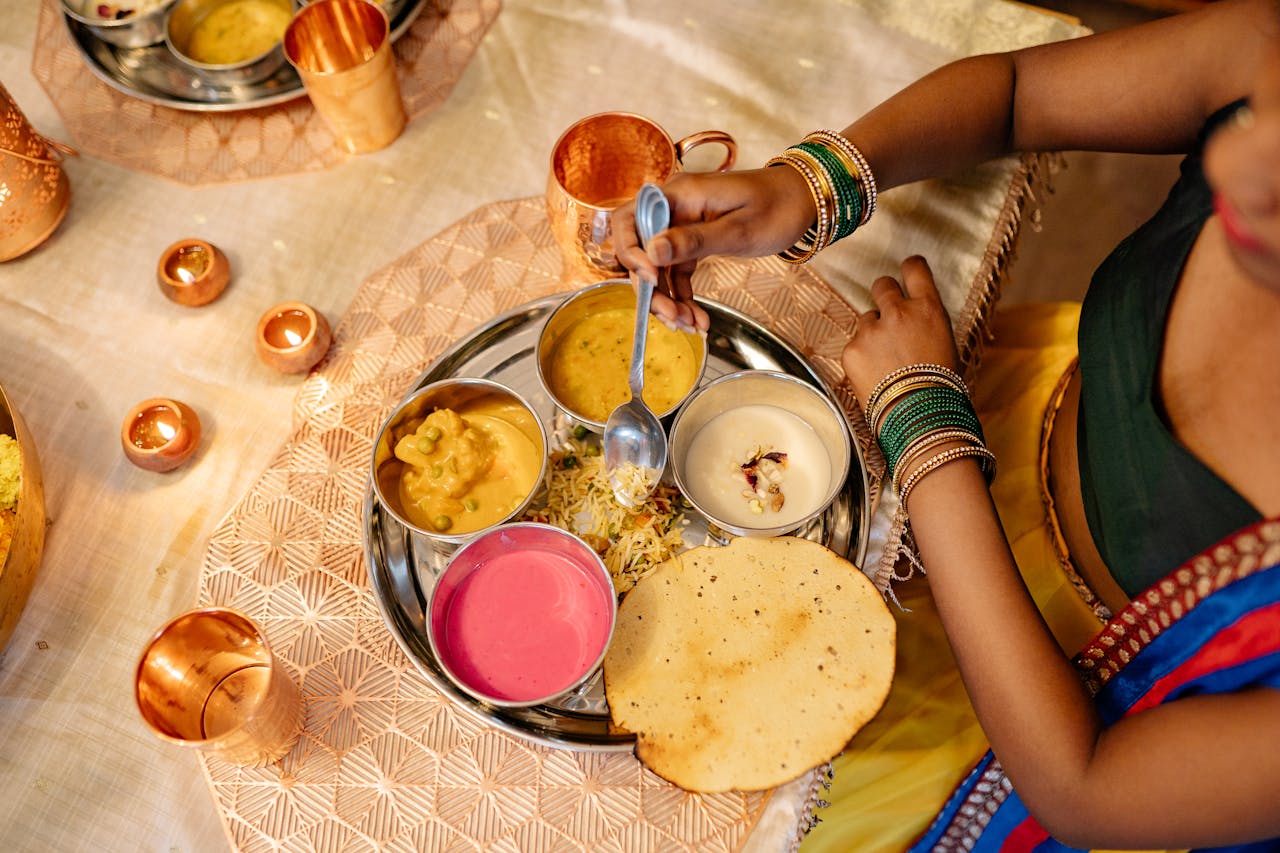 Vibrant Indian thali served during festive occasion with traditional diyas and attire.